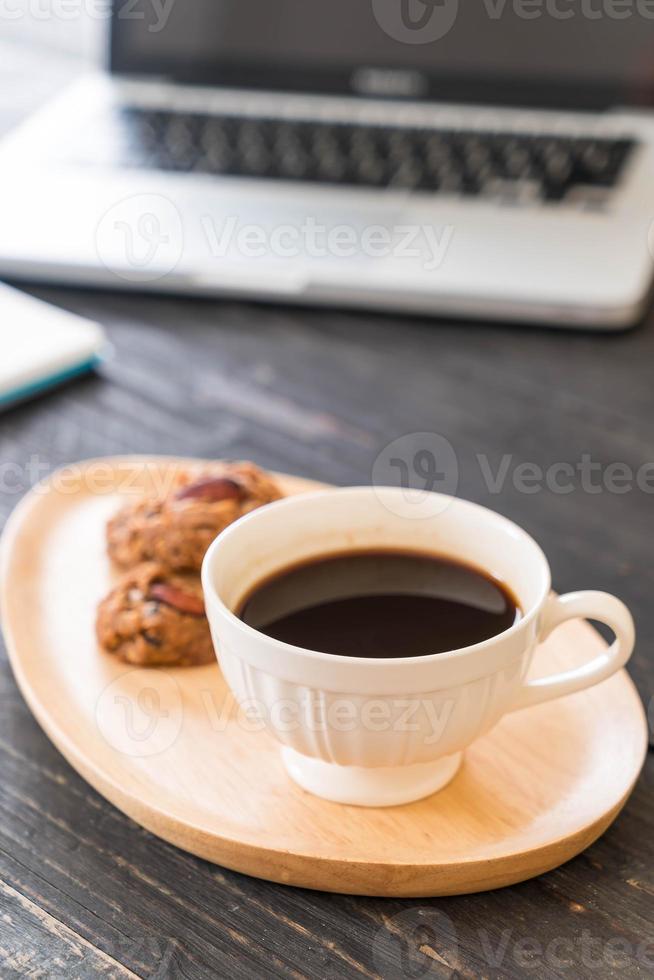 café preto e biscoitos com laptop e notebook na mesa foto