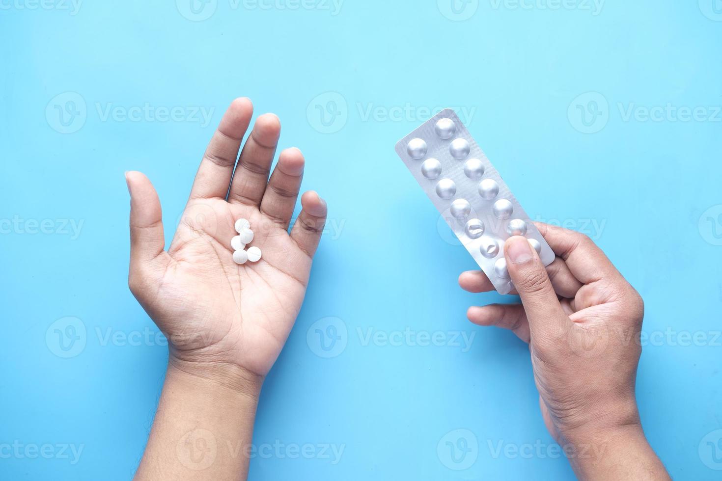 a mão do homem com comprimidos médicos e blister em azul foto