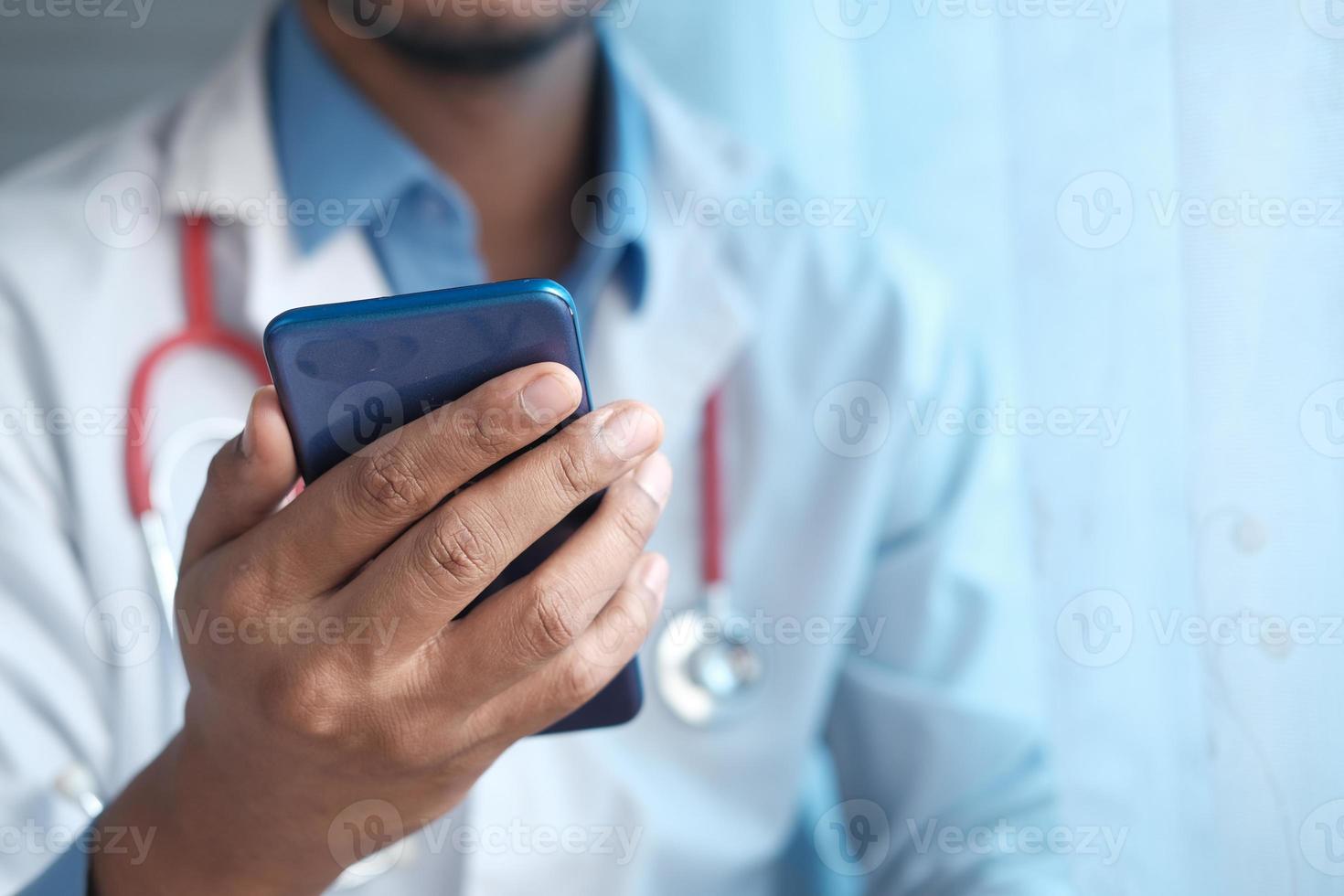 médico de jaleco branco usando um smartphone. foto