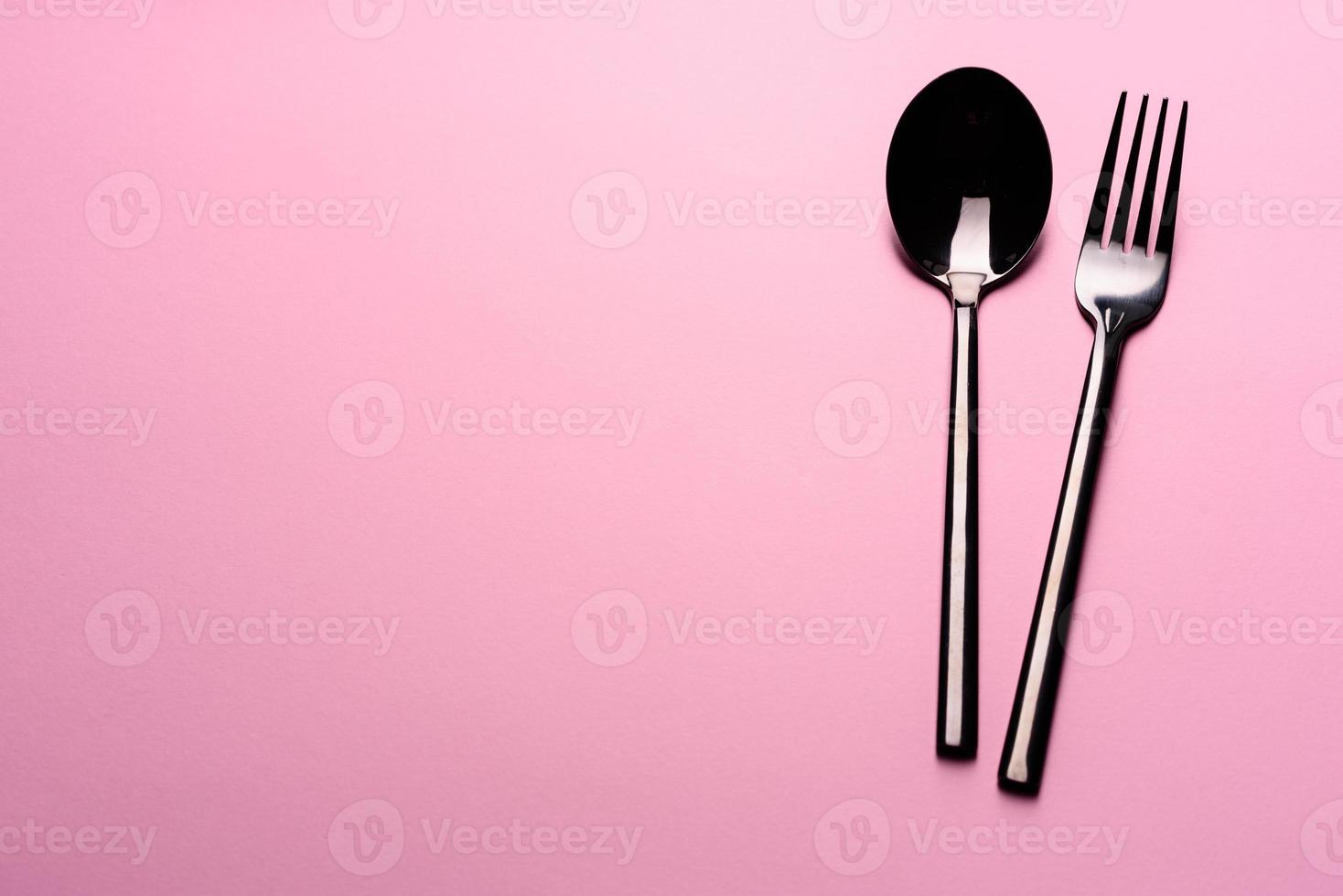 colher de metal e garfo isolados em fundo rosa foto
