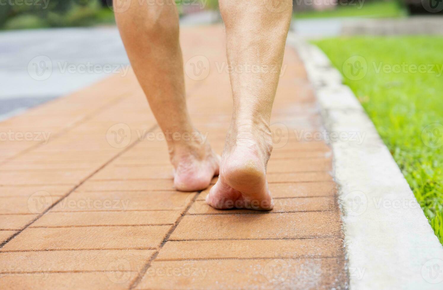 Senior homem descalço caminhando em tijolos passarela dentro a parque foto