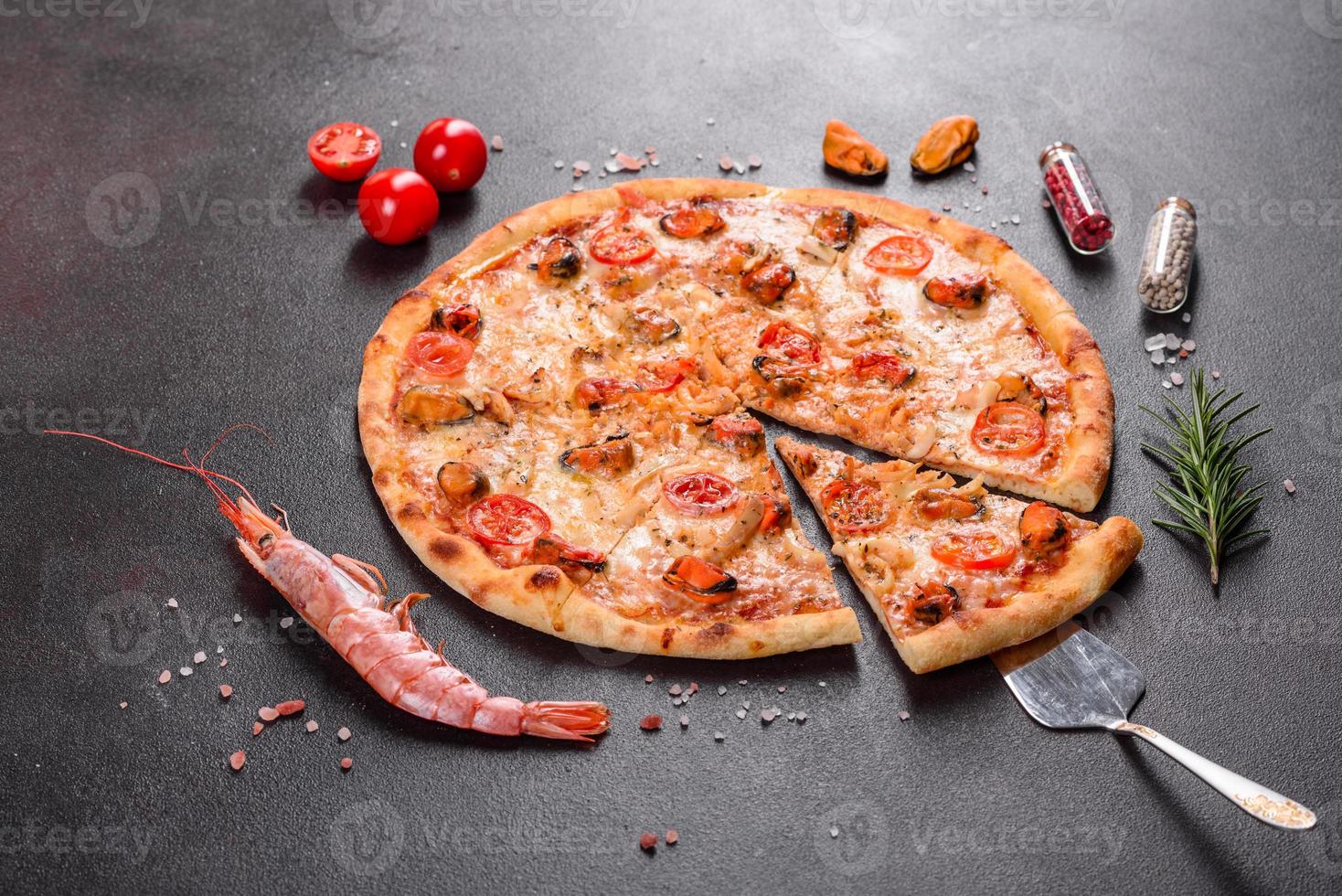 saborosa pizza fatiada com frutos do mar e tomate em um fundo de concreto foto