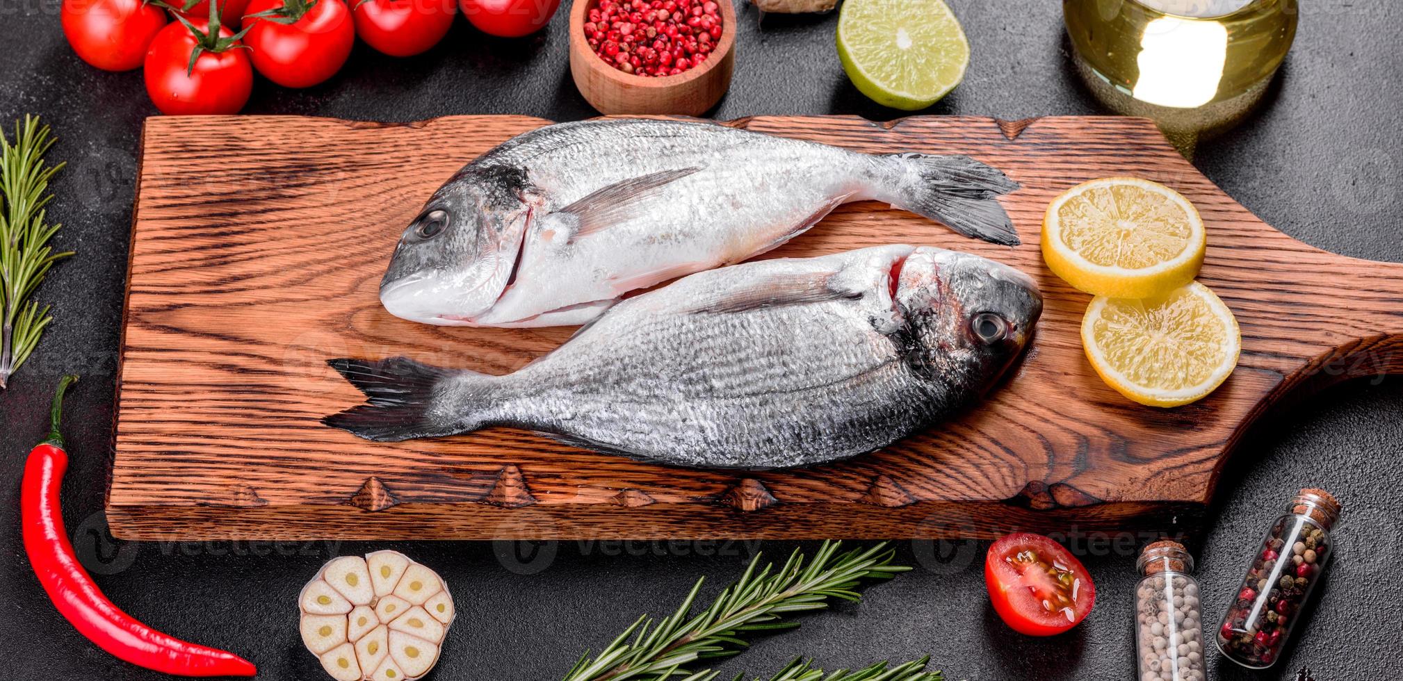 Peixe dourado cru com temperos cozinhando na tábua foto