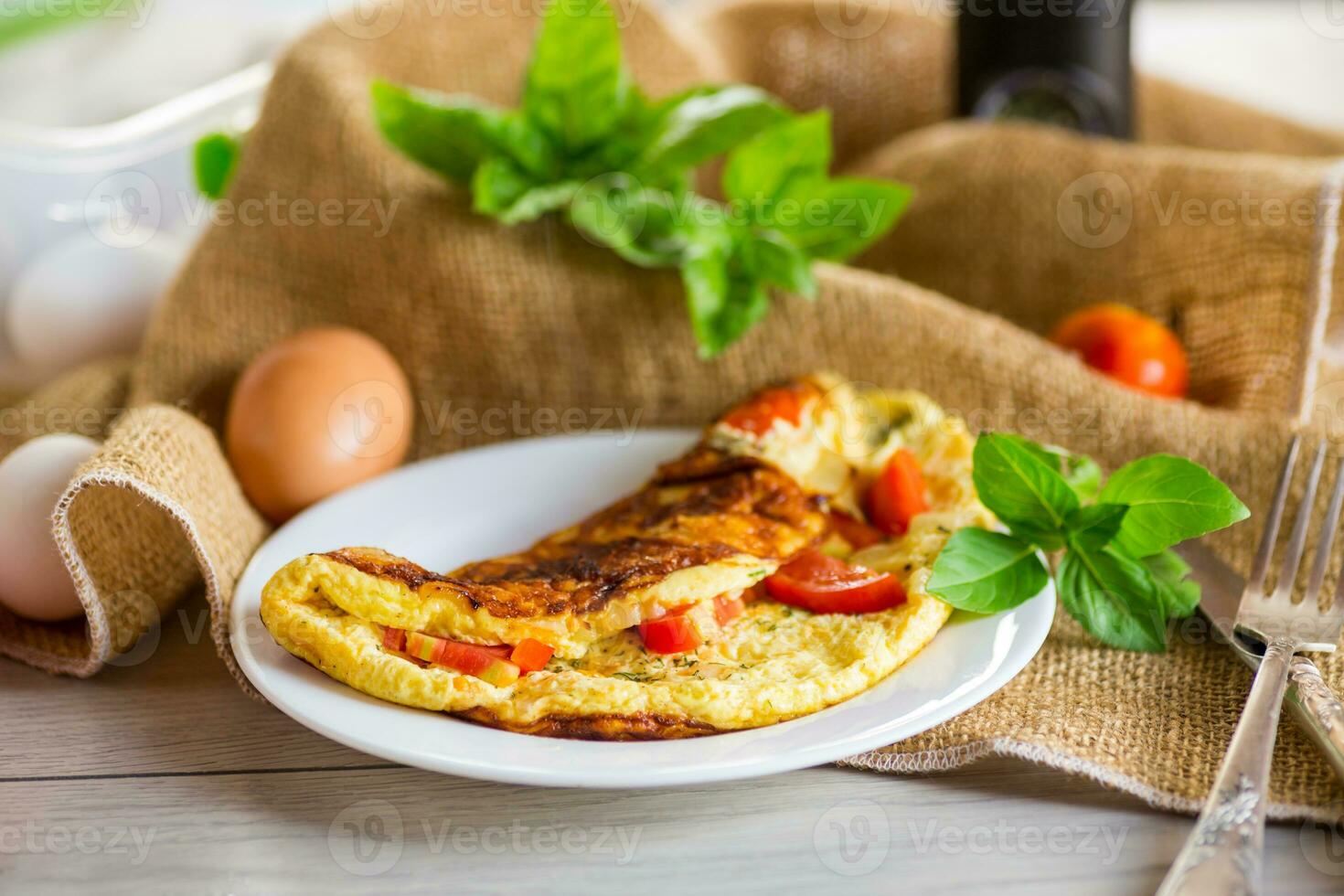 recheado omelete com tomates em uma luz de madeira fundo. foto