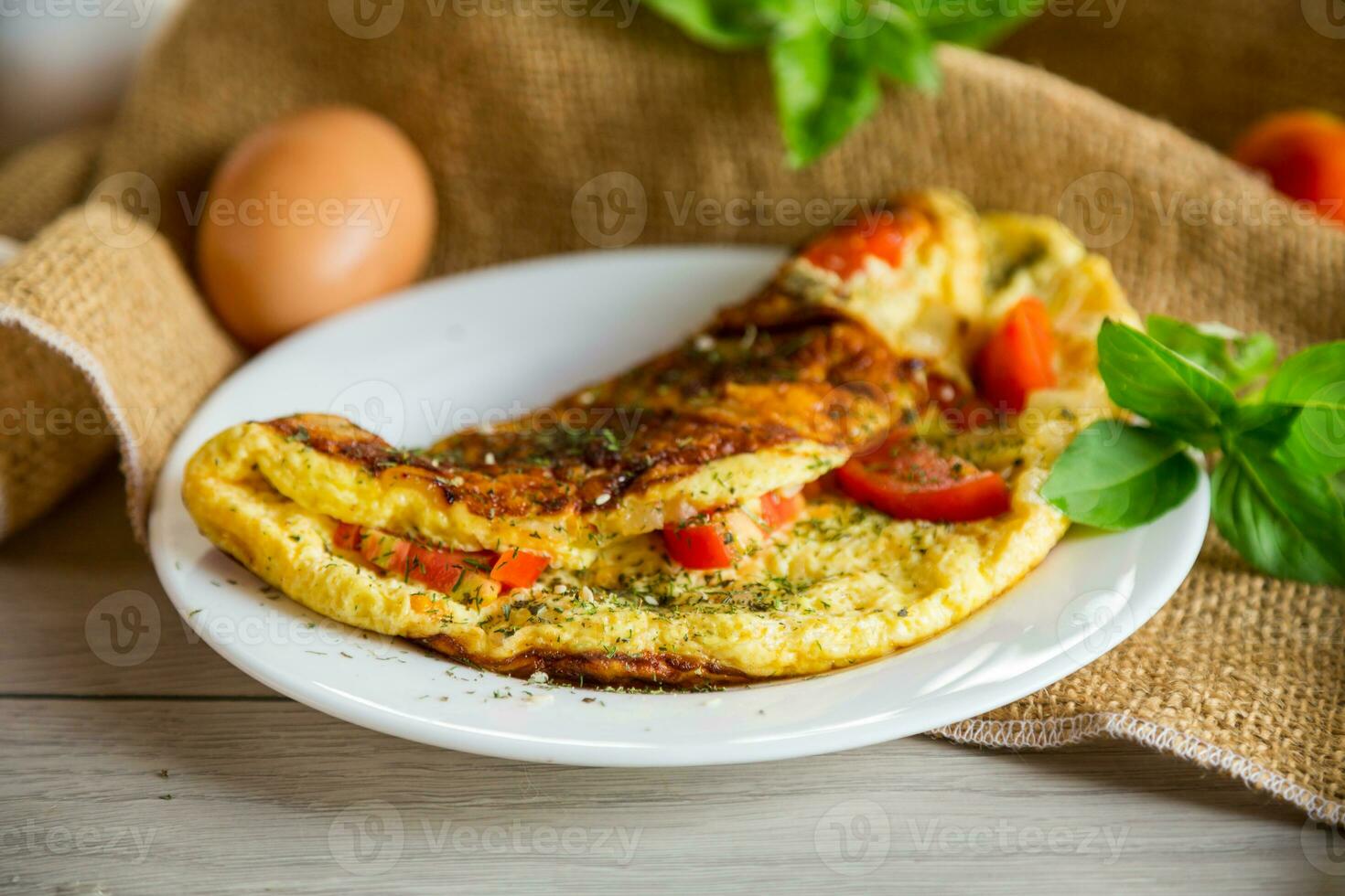 recheado omelete com tomates em uma luz de madeira fundo. foto