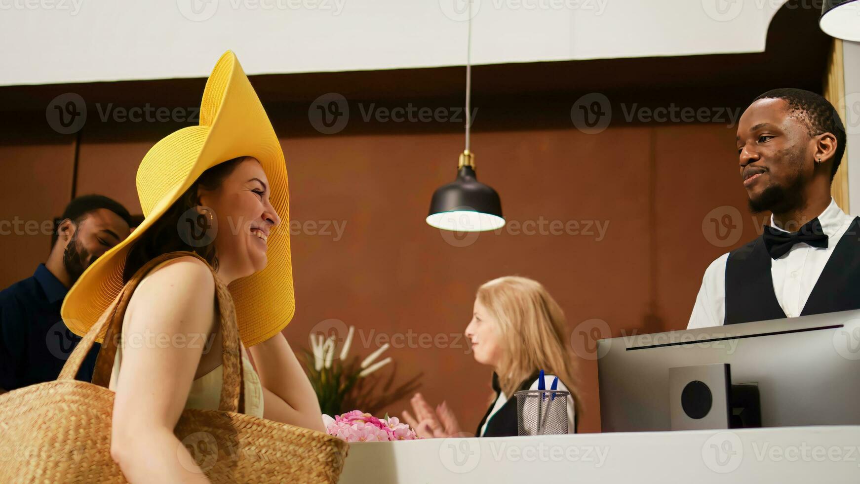 hotel porteiro acolhedor turistas dentro salão, cumprimento casal às frente escrivaninha para Reveja quarto reserva e Faz Verifica em. pessoas em lua de mel desfrutando tropical verão feriado. portátil tomada. foto