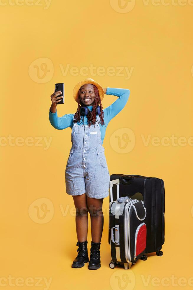 viajante usando Videoconferência bate-papo em Câmera, desfrutando feriado viagem e falando em conectados teleconferência. feliz mulher com carrinho bolsas conversando em Video chamada, urbano aventura destino. foto