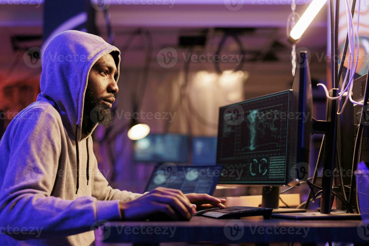 hacker dentro de capuz violar companhia cíber segurança sistema em computador. jovem africano americano homem quebra lei enquanto rachaduras senha e usando Internet vírus malicioso Programas foto