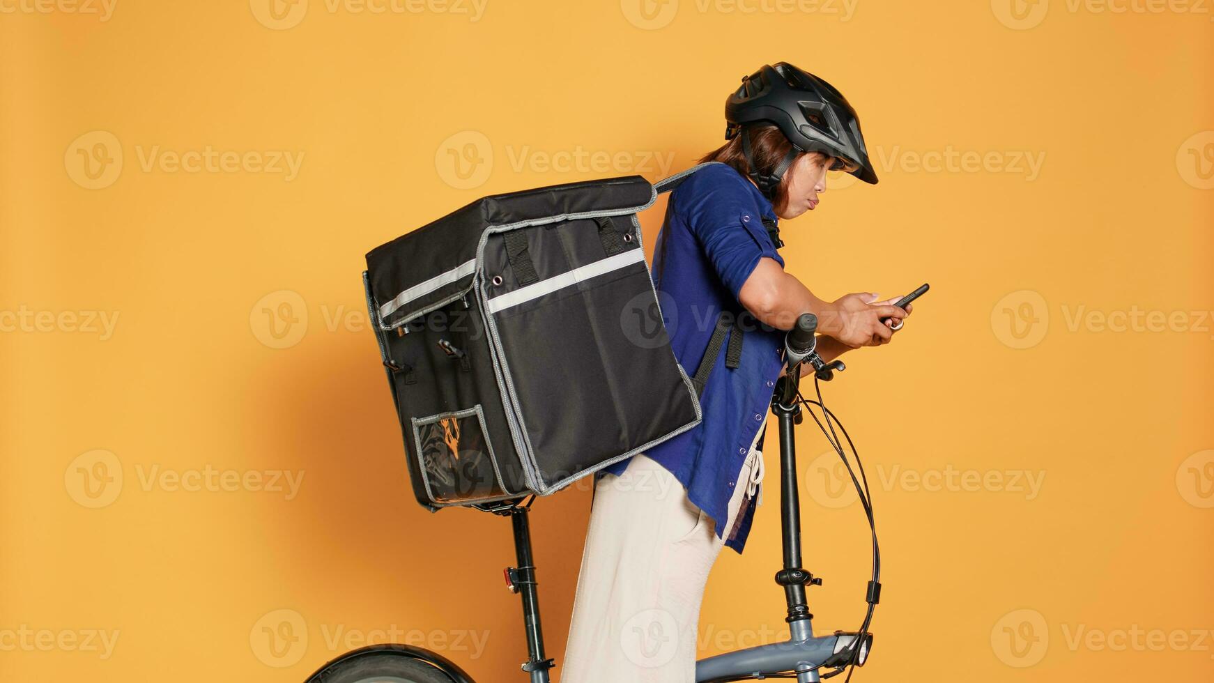 correio conversando com cliente conectados depois de entregando errado Comida ordem. bicicleta cavaleiro vestindo protetora engrenagem e térmico mochila segurando Leve embora refeição, isolado sobre laranja estúdio fundo foto