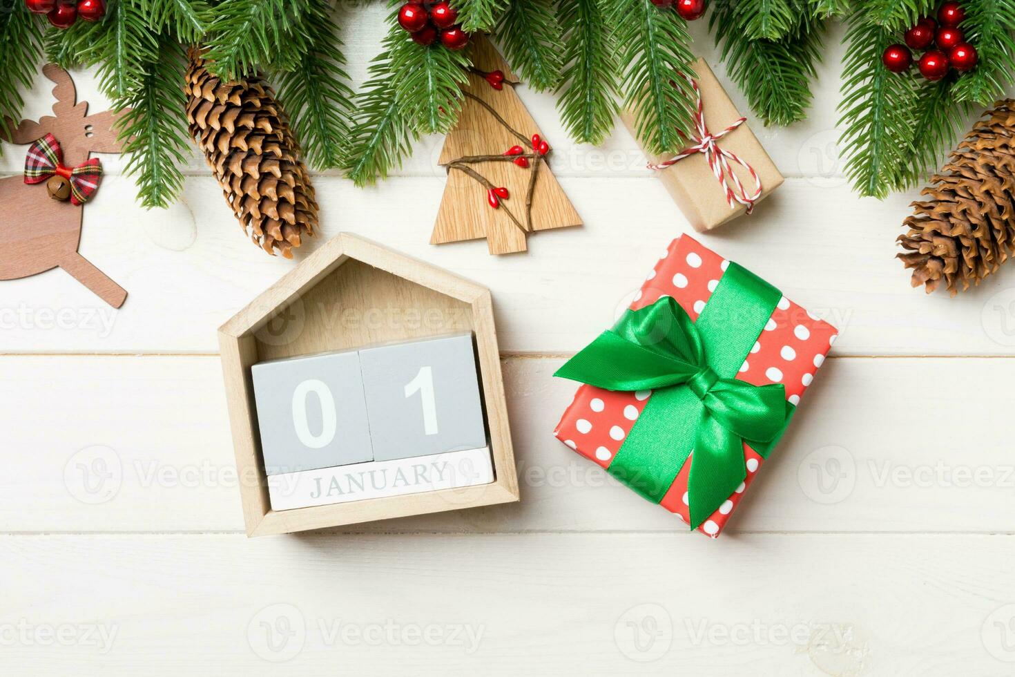vista superior da árvore do abeto, decorações de natal, presente e calendário em fundo de madeira. o primeiro de Janeiro. conceito de ano novo foto