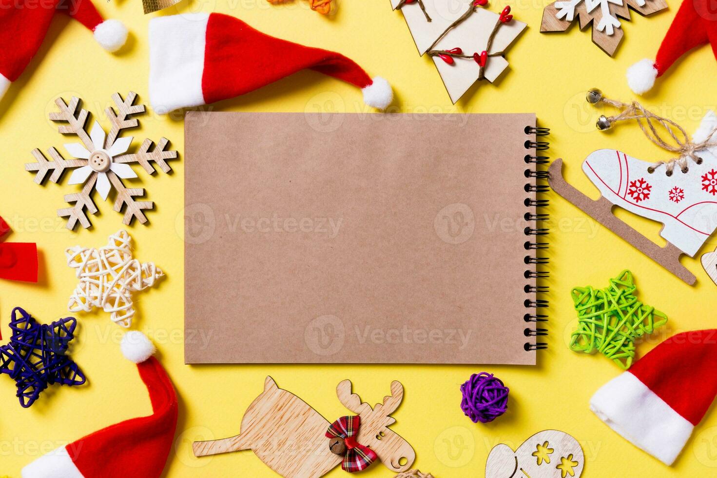 vista superior do notebook com decorações de natal e chapéus de papai noel em fundo amarelo. conceito de feliz feriado foto