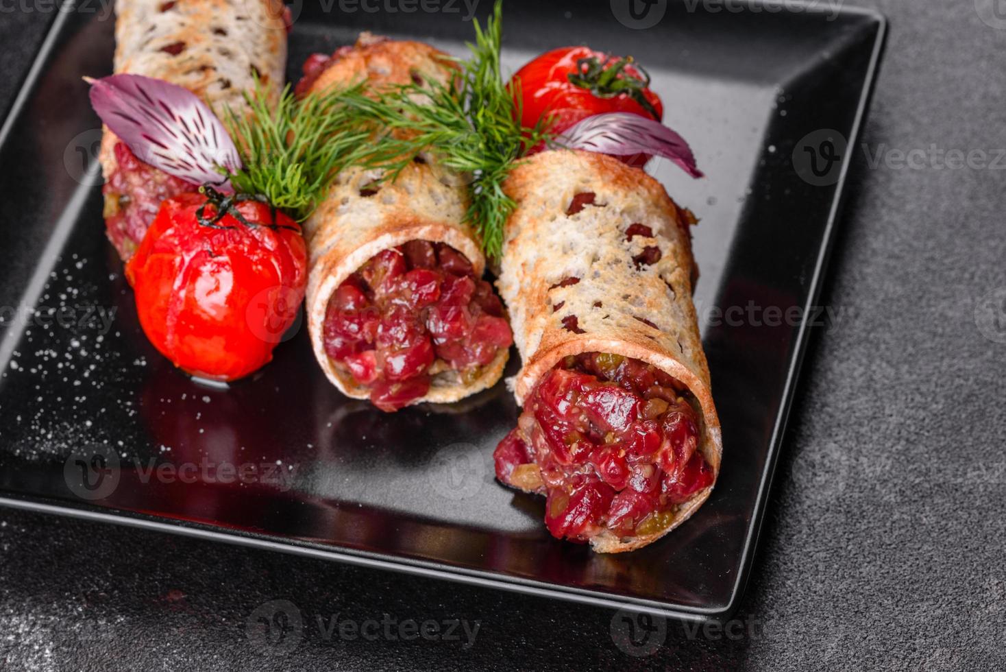 delicioso tártaro de vaca fresco com torradas em um prato quadrado preto foto