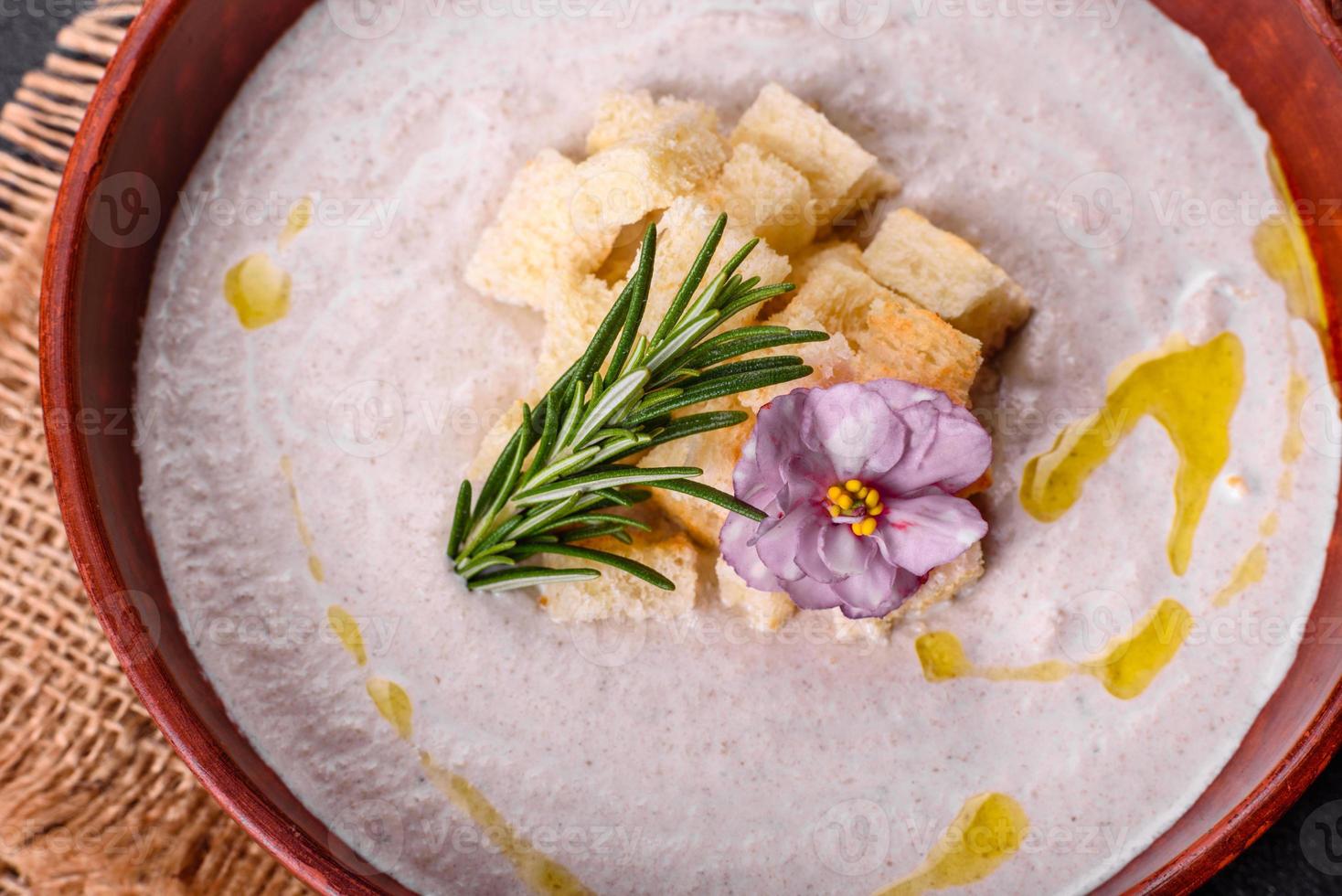 deliciosa e linda sopa de cogumelos em um prato marrom com uma colher de pau foto