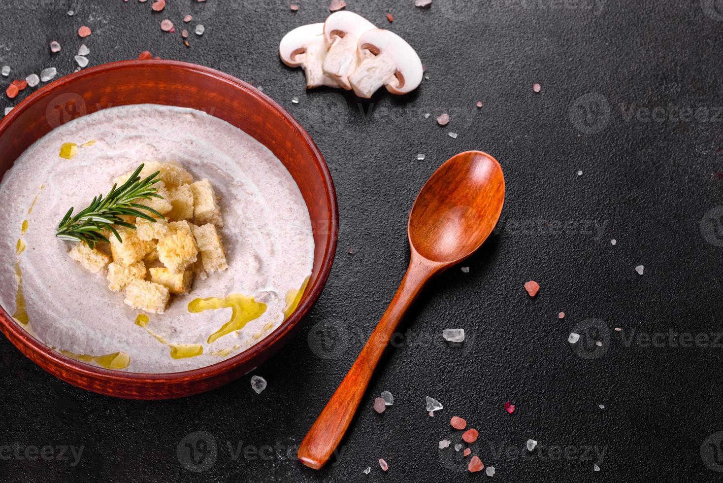 deliciosa e linda sopa de cogumelos em um prato marrom com uma colher de pau foto