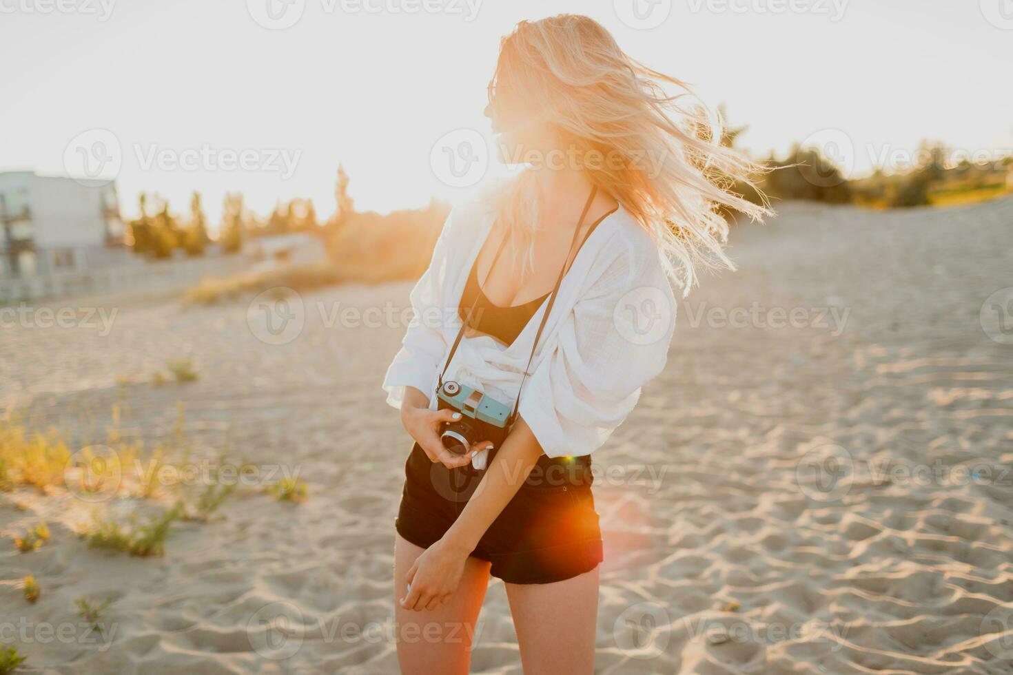 à moda bem torneado menina com retro Câmera posando em ensolarado tarde de praia. tropical humor. foto