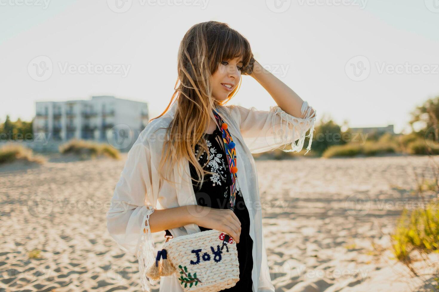 romântico menina com grandes cabelo caminhando em a de praia. boêmio estilo, Palha saco , brilhante faço acima. foto