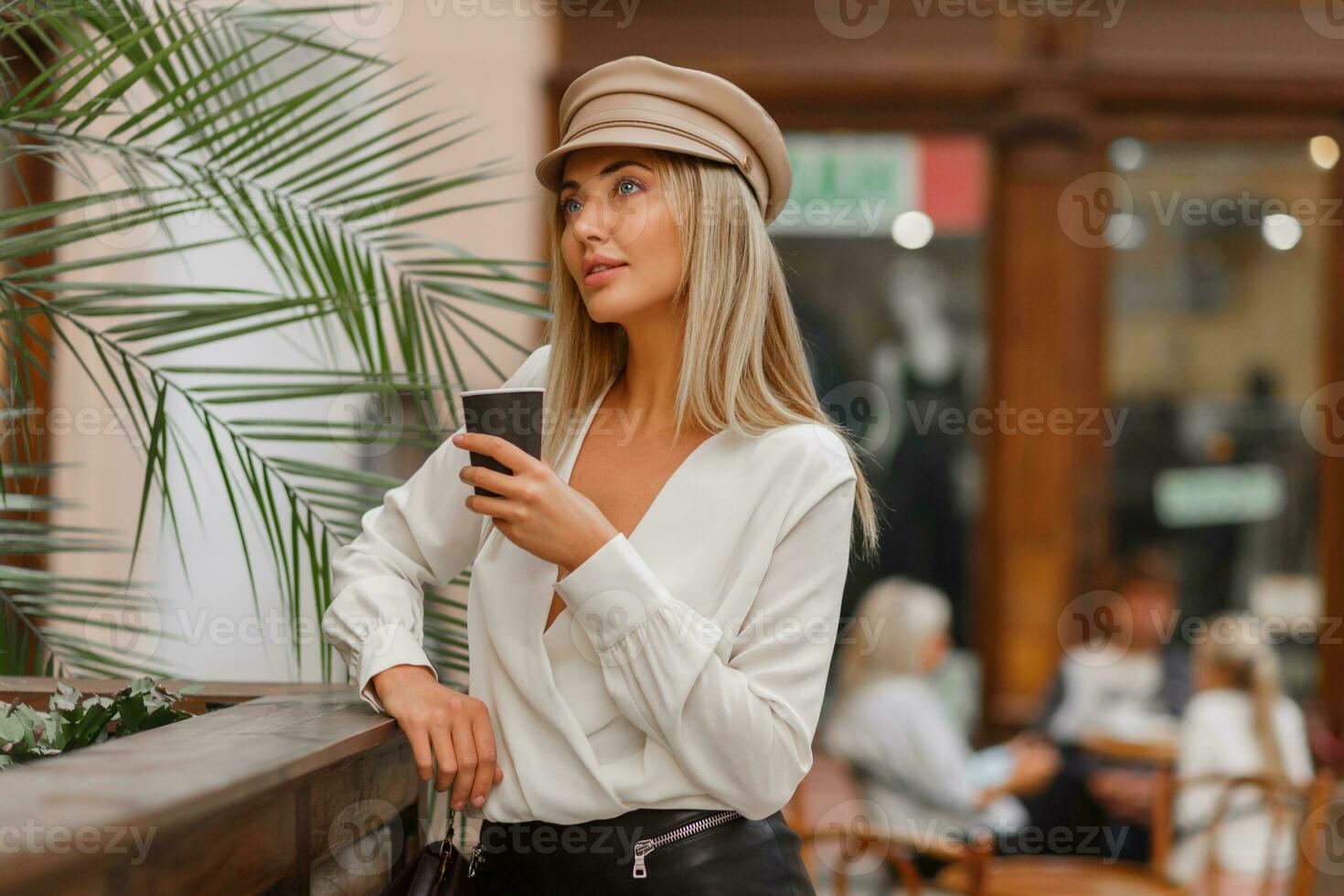 romântico bonita loiro mulher desfrutando quente café ar livre. vestindo bege na moda boina. outono humor. foto