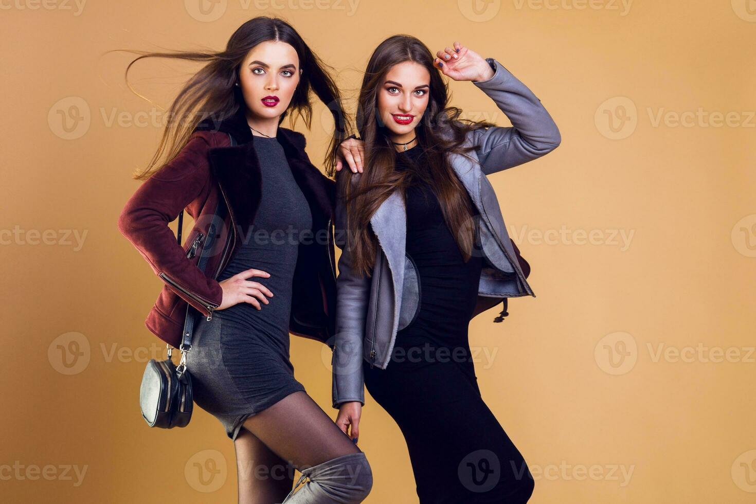 dois moda modelos dentro inverno ou outono roupas posando dentro estúdio em bege fundo. elegante casual jaqueta, Alto salto. cheio comprimento imagem. foto