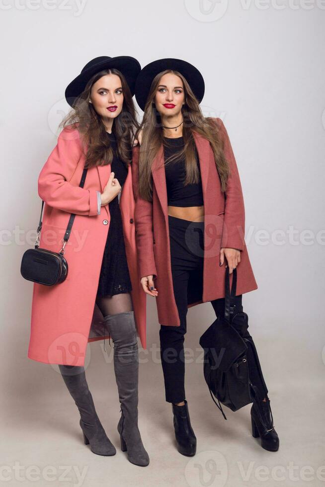 dois irmãs andando. altura moda olhar. na moda Primavera roupas. casual modelos posando em cinzento fundo. espaço para texto. foto