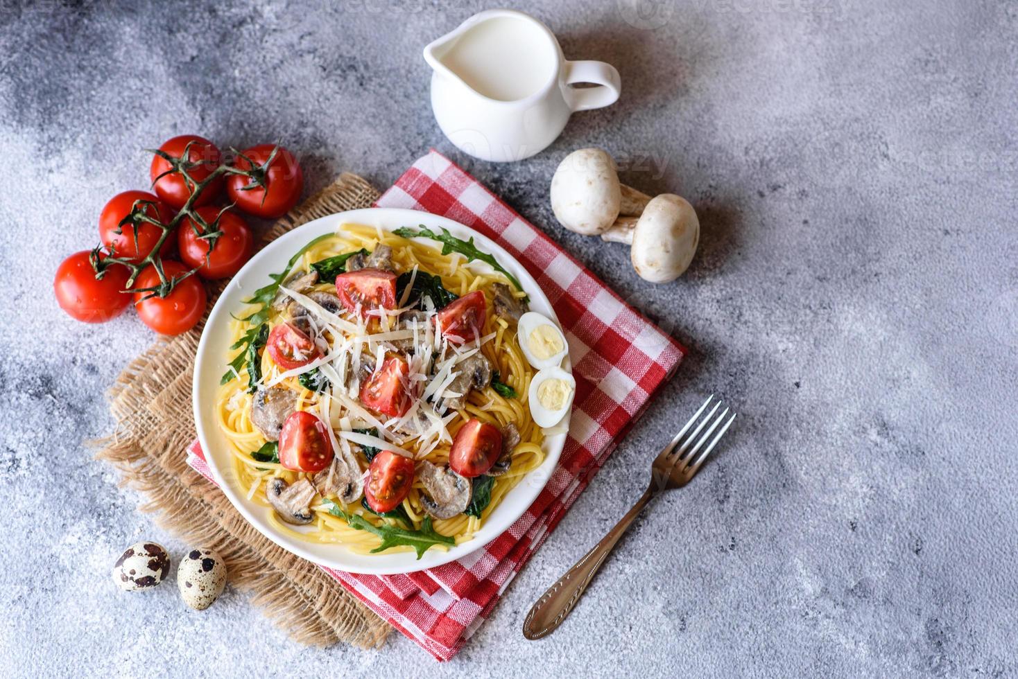 espaguete com cogumelos, queijo, espinafre, rukkola e tomate cereja foto