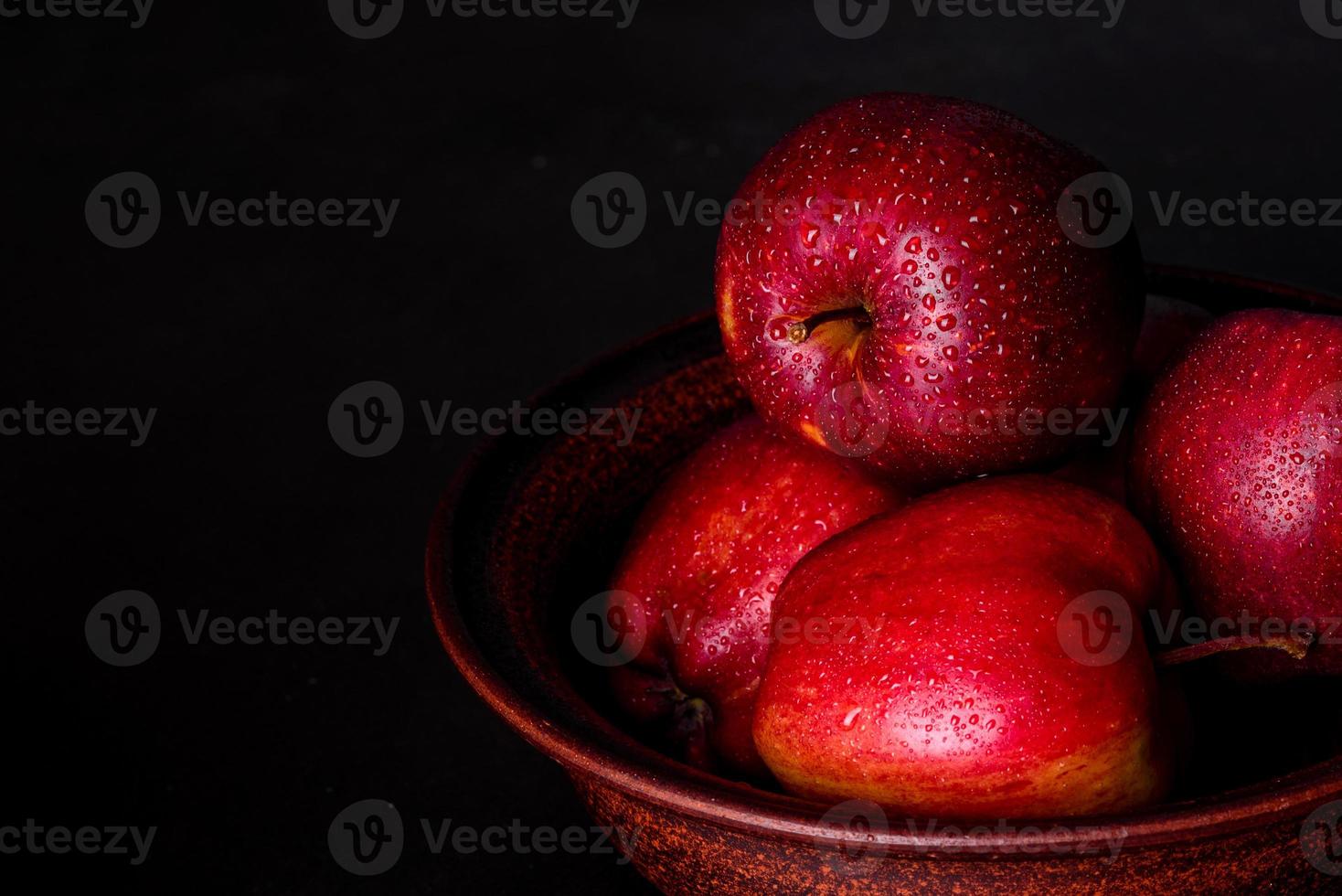 Suculenta maçã vermelha fresca com gotas de água contra um fundo escuro foto