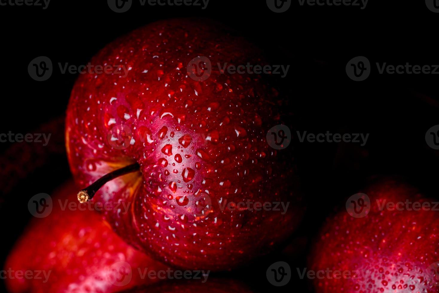 Suculenta maçã vermelha fresca com gotas de água contra um fundo escuro foto