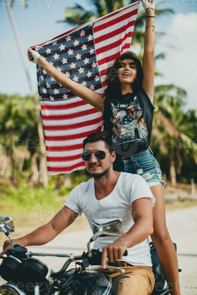 jovem casal dentro amor, equitação uma motocicleta, abraço, paixão, livre espírito, americano bandeira foto