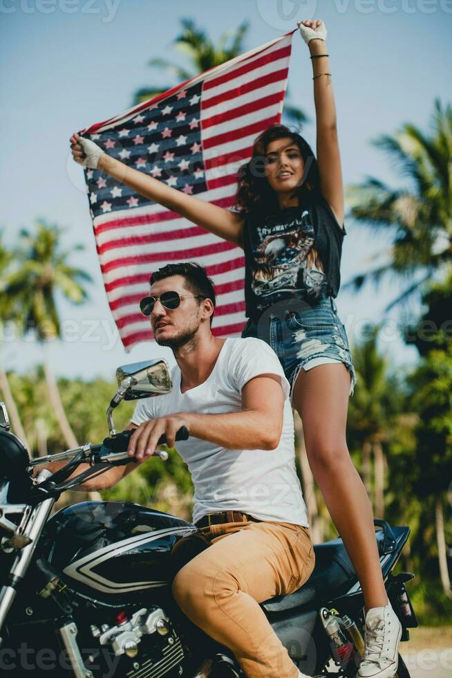 jovem casal dentro amor, equitação uma motocicleta, abraço, paixão, livre espírito, americano bandeira foto