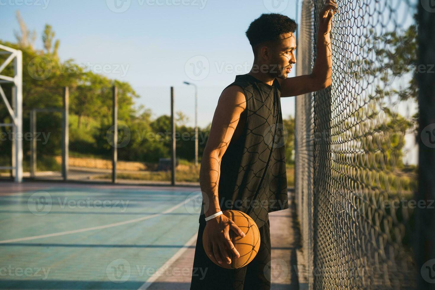 Preto homem fazendo Esportes, jogando basquetebol em nascer do sol, ativo estilo de vida, ensolarado verão manhã foto