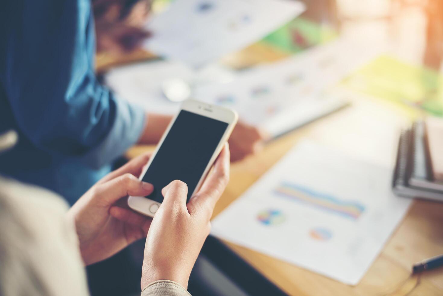 mãos de mulher de negócios trabalhando em telefone inteligente e informações de negócios foto