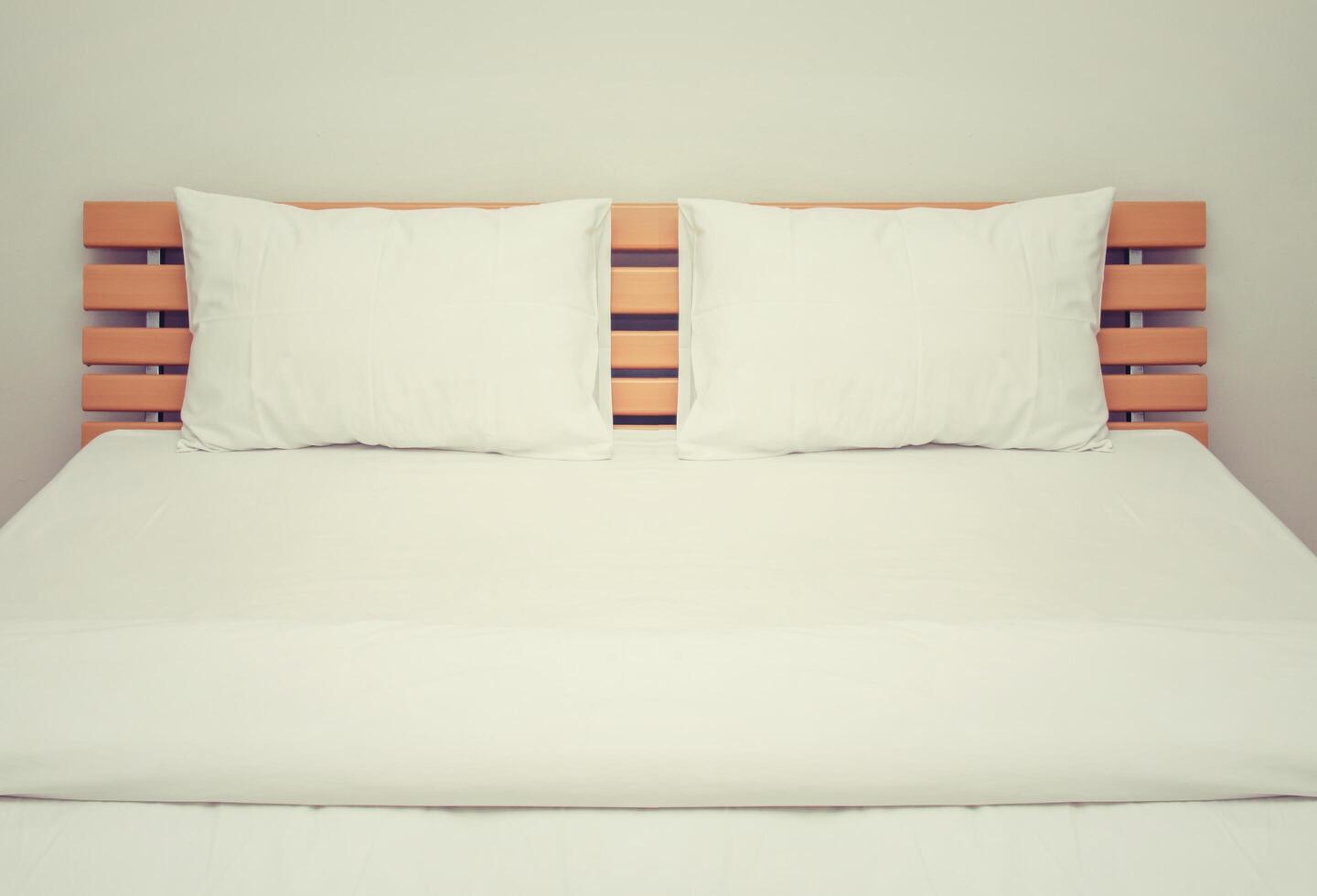 cobertores e travesseiros brancos na cama de madeira do quarto foto
