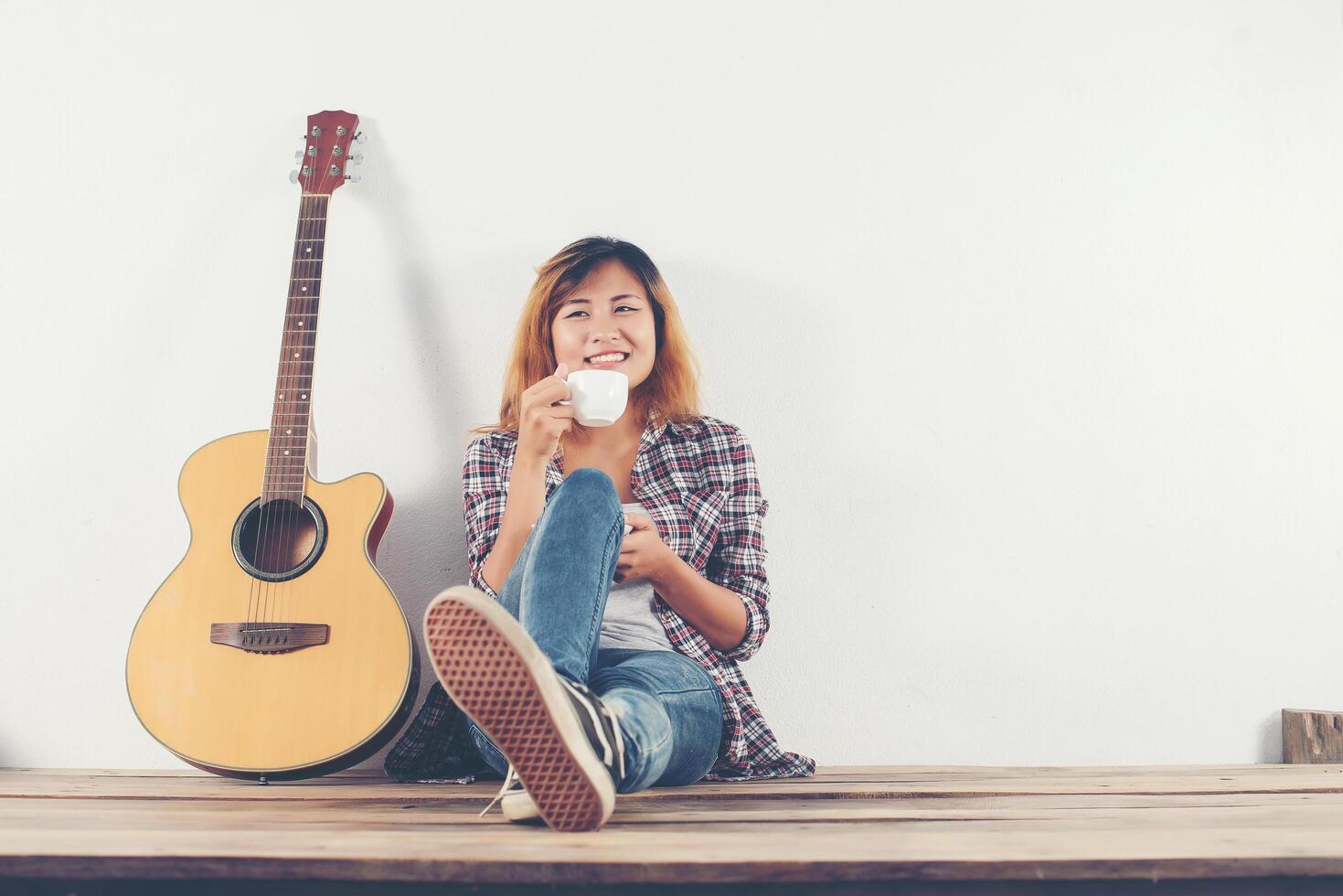 mulher jovem hippie bebendo café relaxando com sessão de guitarra. foto