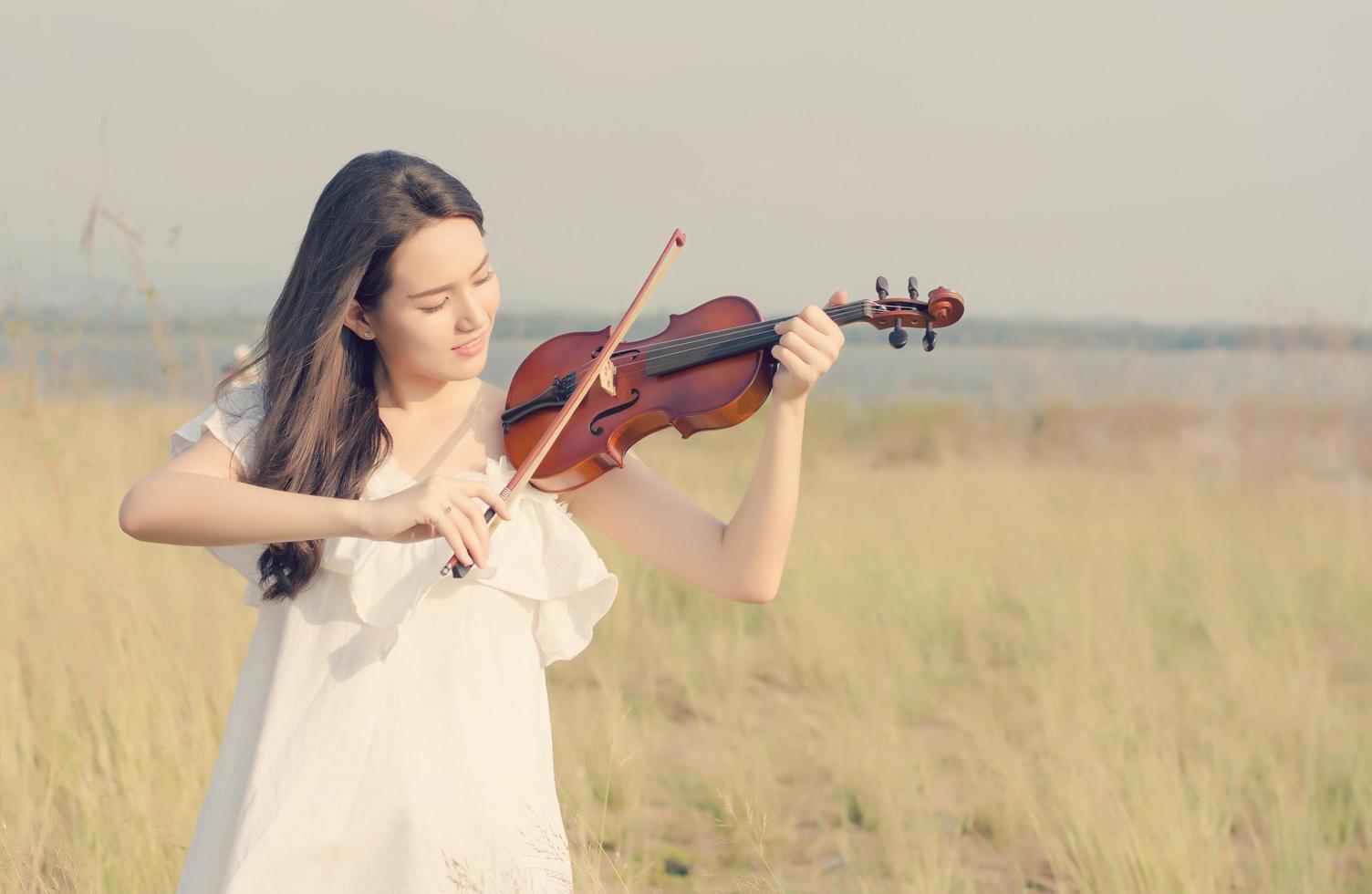 linda mulher em pé tocando violino na campina foto