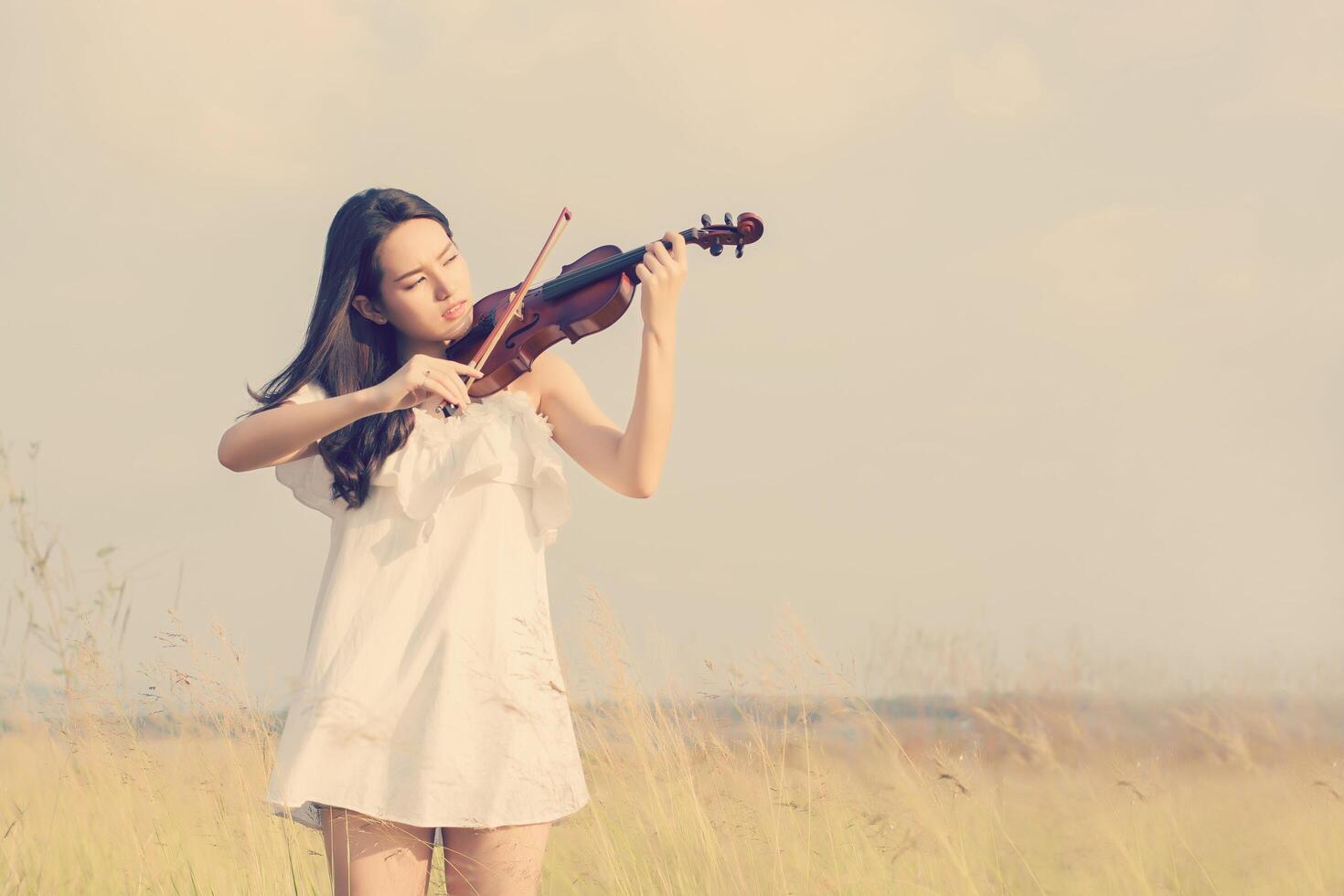 linda mulher em pé tocando violino na campina foto