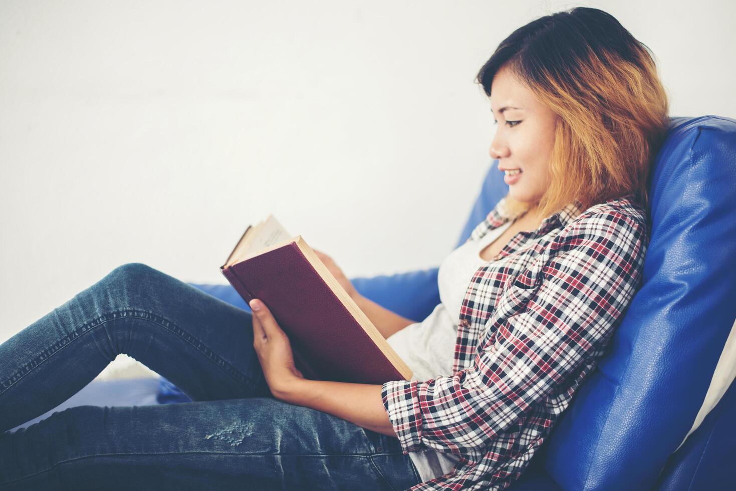 mulher lendo livros e deitada no sofá em casa. foto