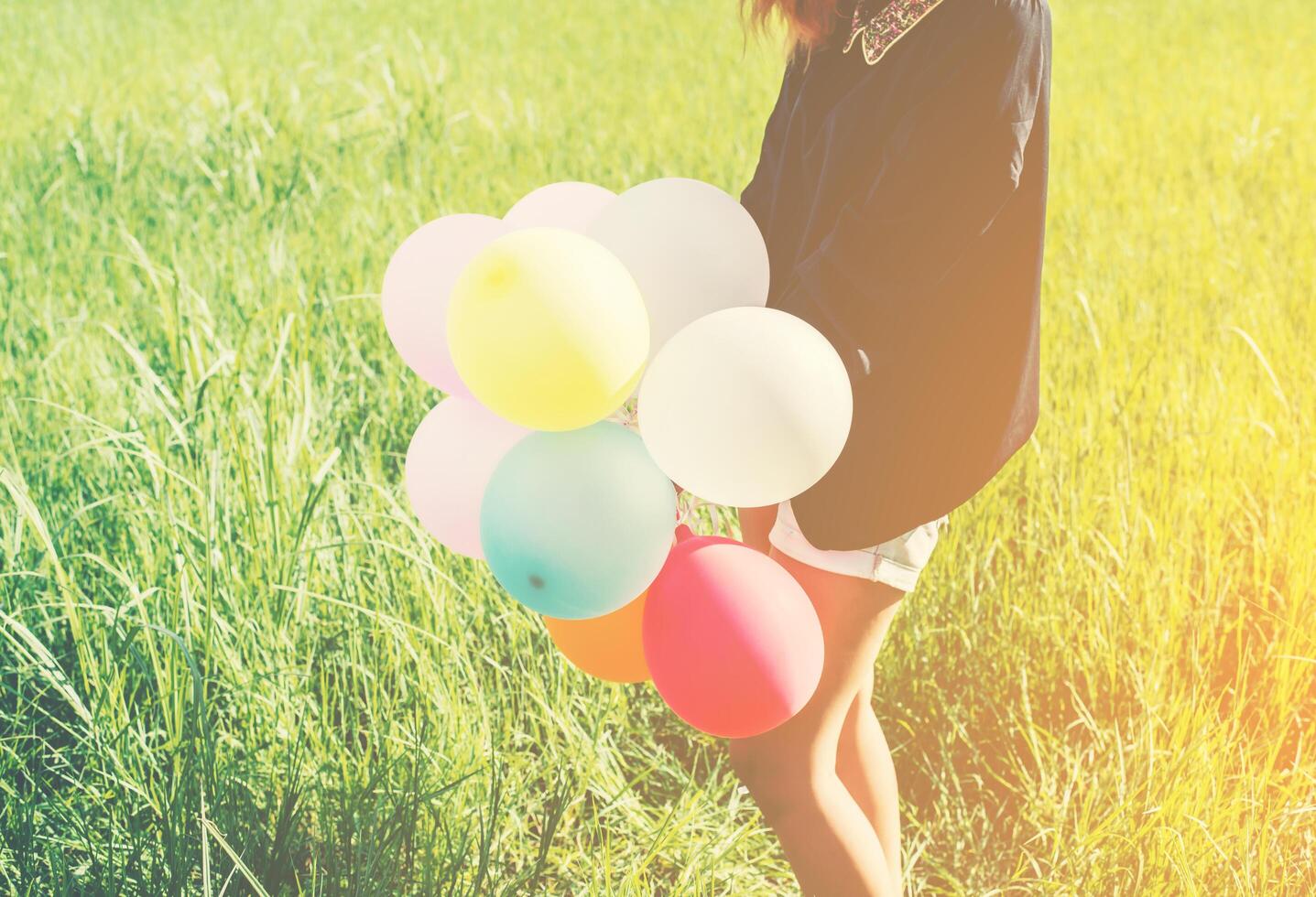 mulher bonita jovem feliz e balões coloridos em pastagens. foto