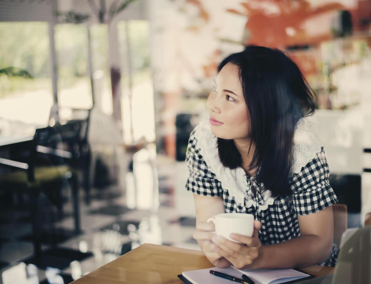 bela jovem sentada segurando uma xícara de café em um café, aproveitando o tempo foto