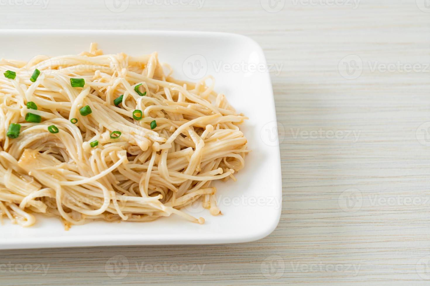 Cogumelo agulha dourado frito com manteiga no prato branco foto