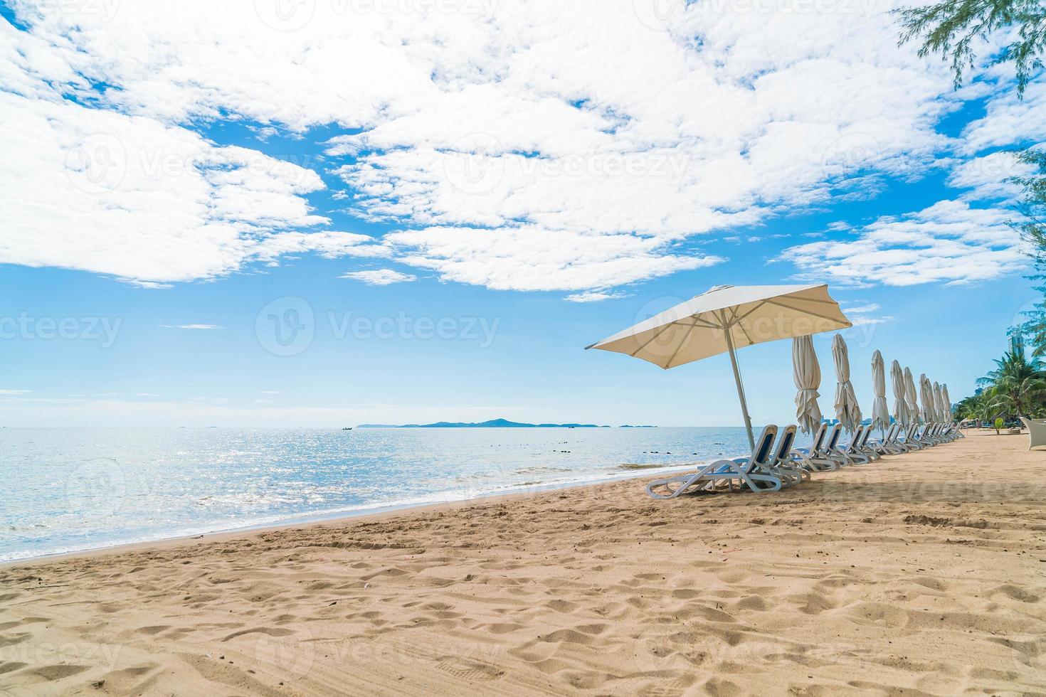 ao ar livre com guarda-sol e cadeira na bela praia tropical e mar foto