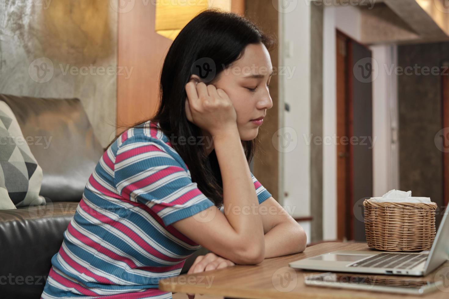 mulher asiática trabalhando em casa, cochilando e cochilando atrás de um laptop. foto