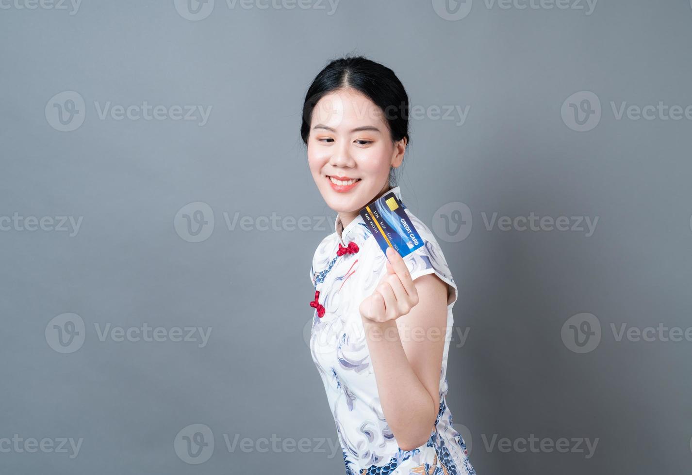 Mulher asiática usando vestido tradicional chinês com a mão segurando um cartão foto