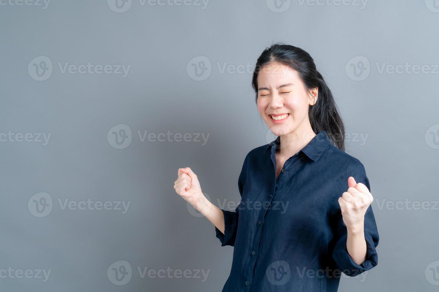 mulher asiática comemorando seu sucesso e a vitória apertada de alegria foto