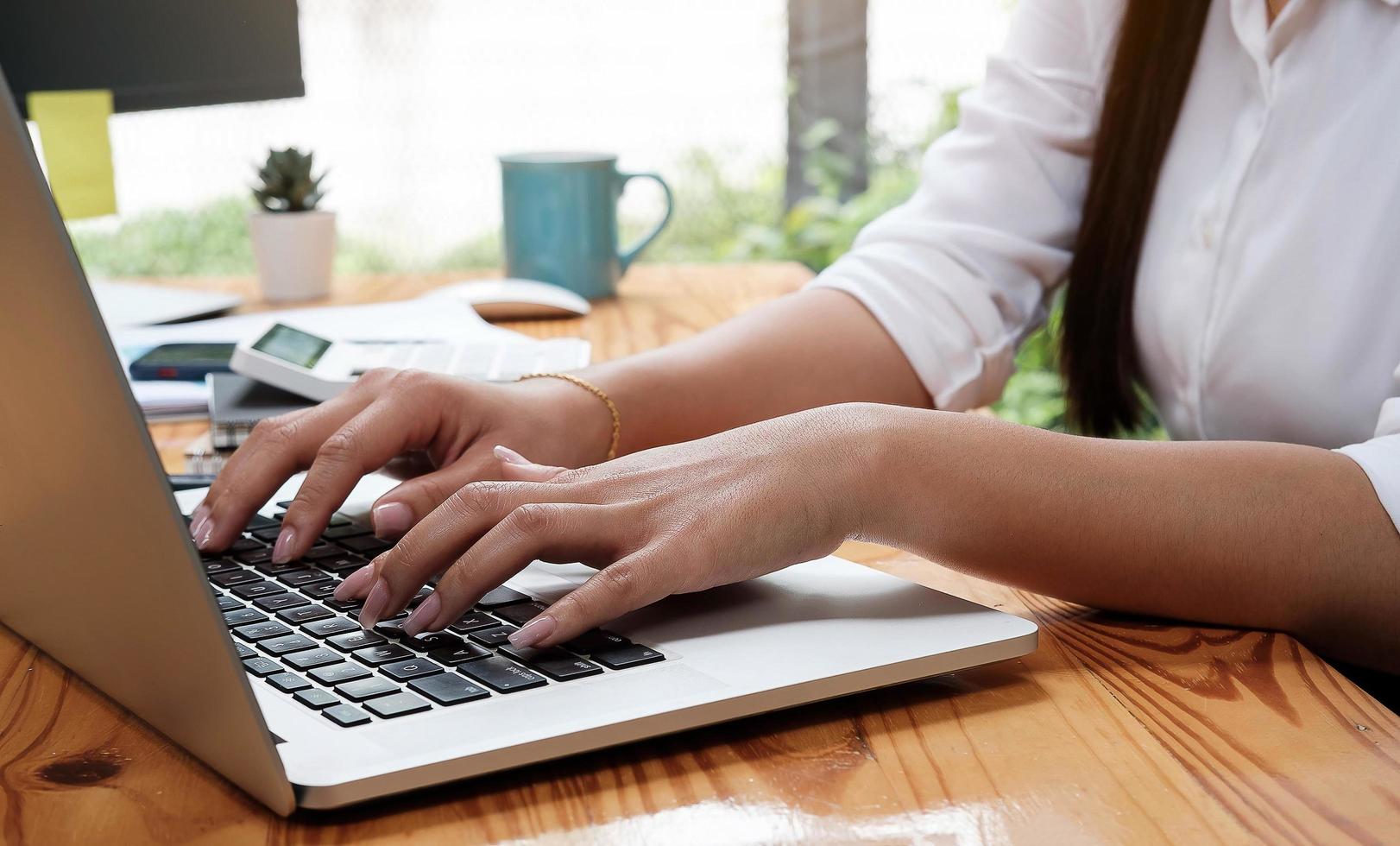 imagem aproximada de uma mulher de negócios asiática trabalhando e digitando em um laptop foto