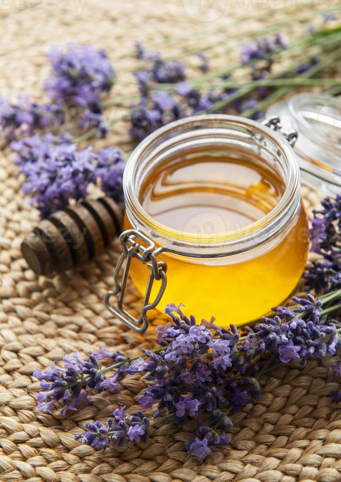 jarra com mel e flores frescas de lavanda foto