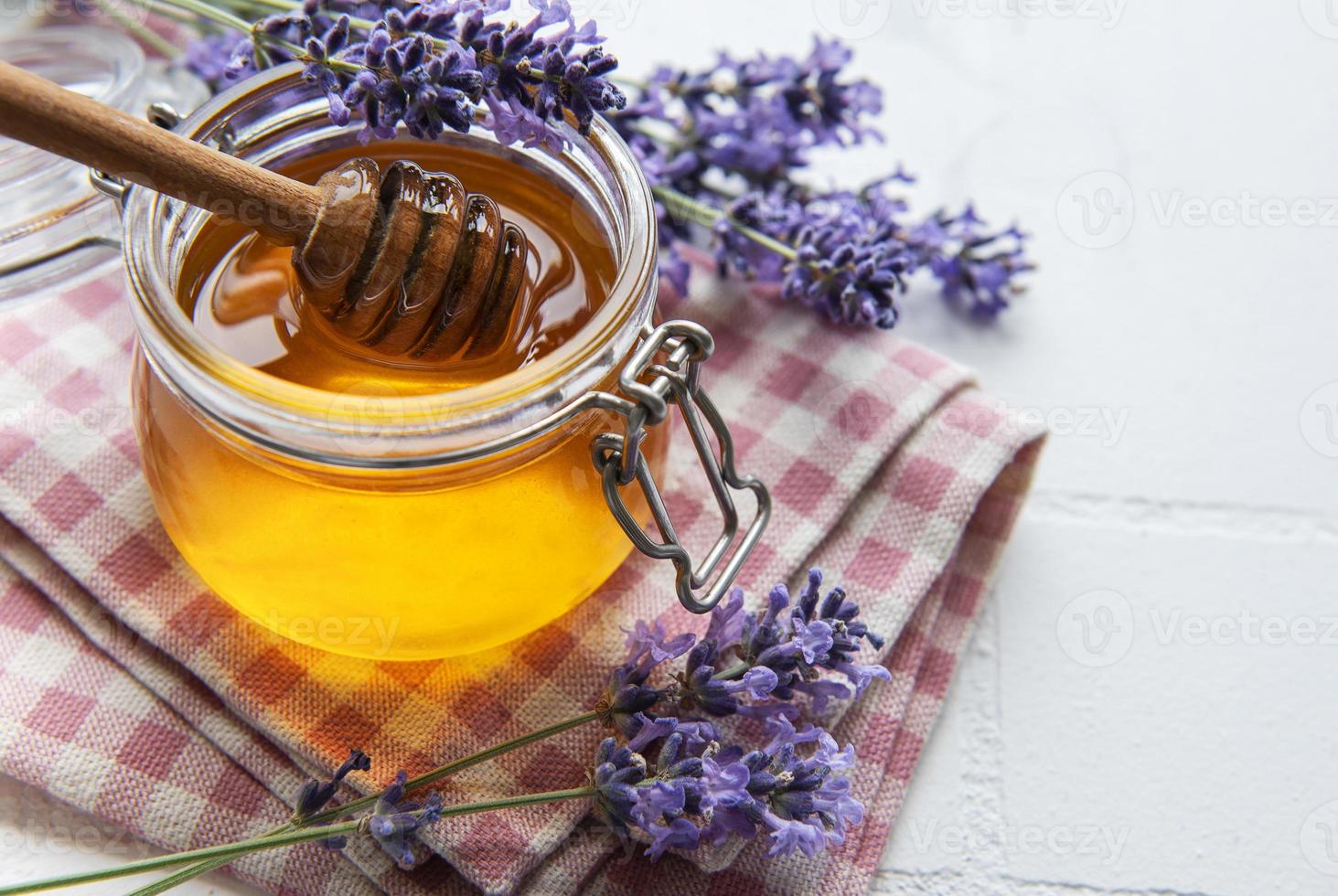 jarra com mel e flores frescas de lavanda foto