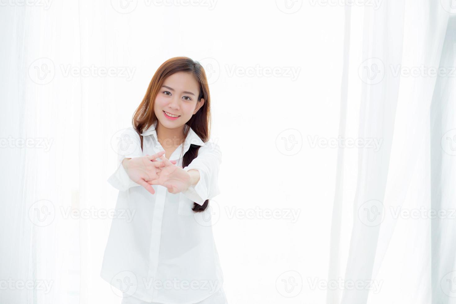 jovem asiática se espreguiçando e relaxando em pé na cama depois de acordar foto