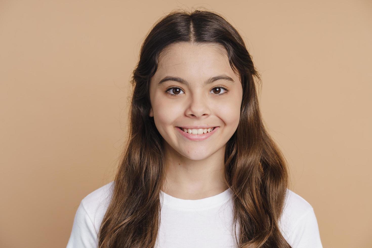 adolescente sorridente e positiva posando em um fundo marrom foto