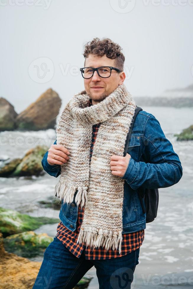 homem viajante com uma mochila em uma rocha contra um lindo mar foto