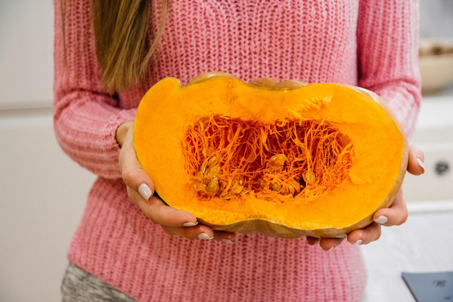 mulher segurando uma abóbora fatiada foto