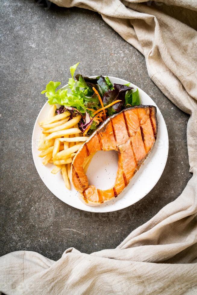 Filé de Salmão Grelhado com Legumes e Batatas Fritas no Prato foto